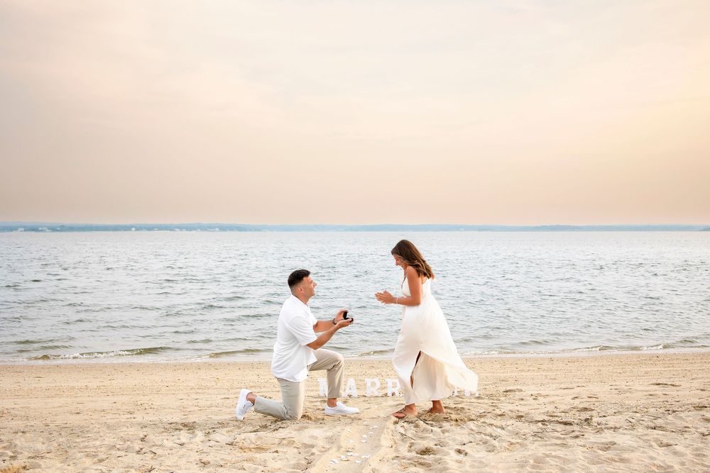 Family in white clothing poses playfully on a sandy beach at sunset while creating joyful memories together.