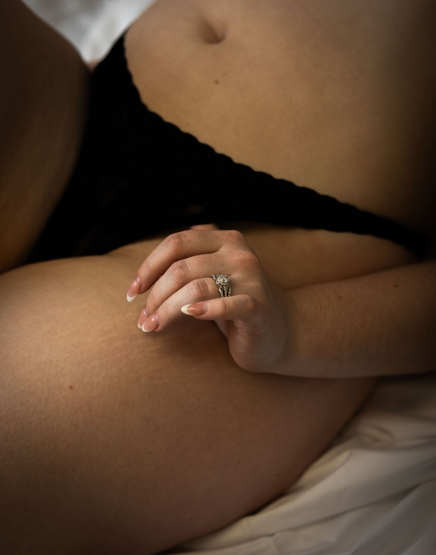 Detailed shot of hand with elegant ring against soft white bedding.