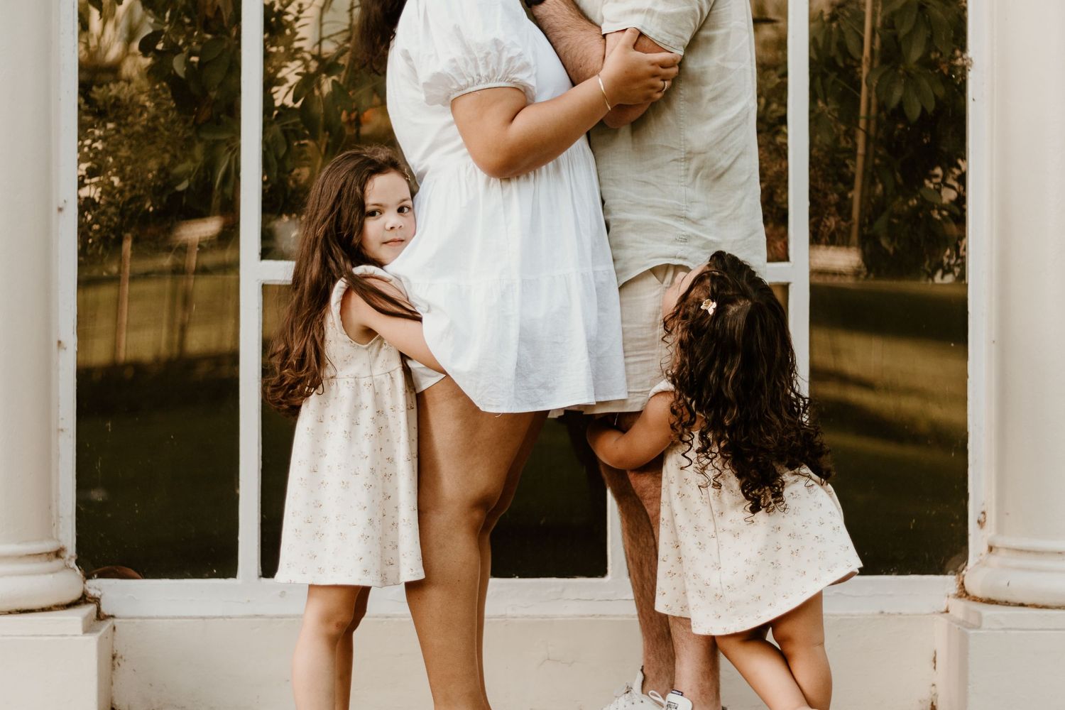 Two daughters hugging their mother and father's legs