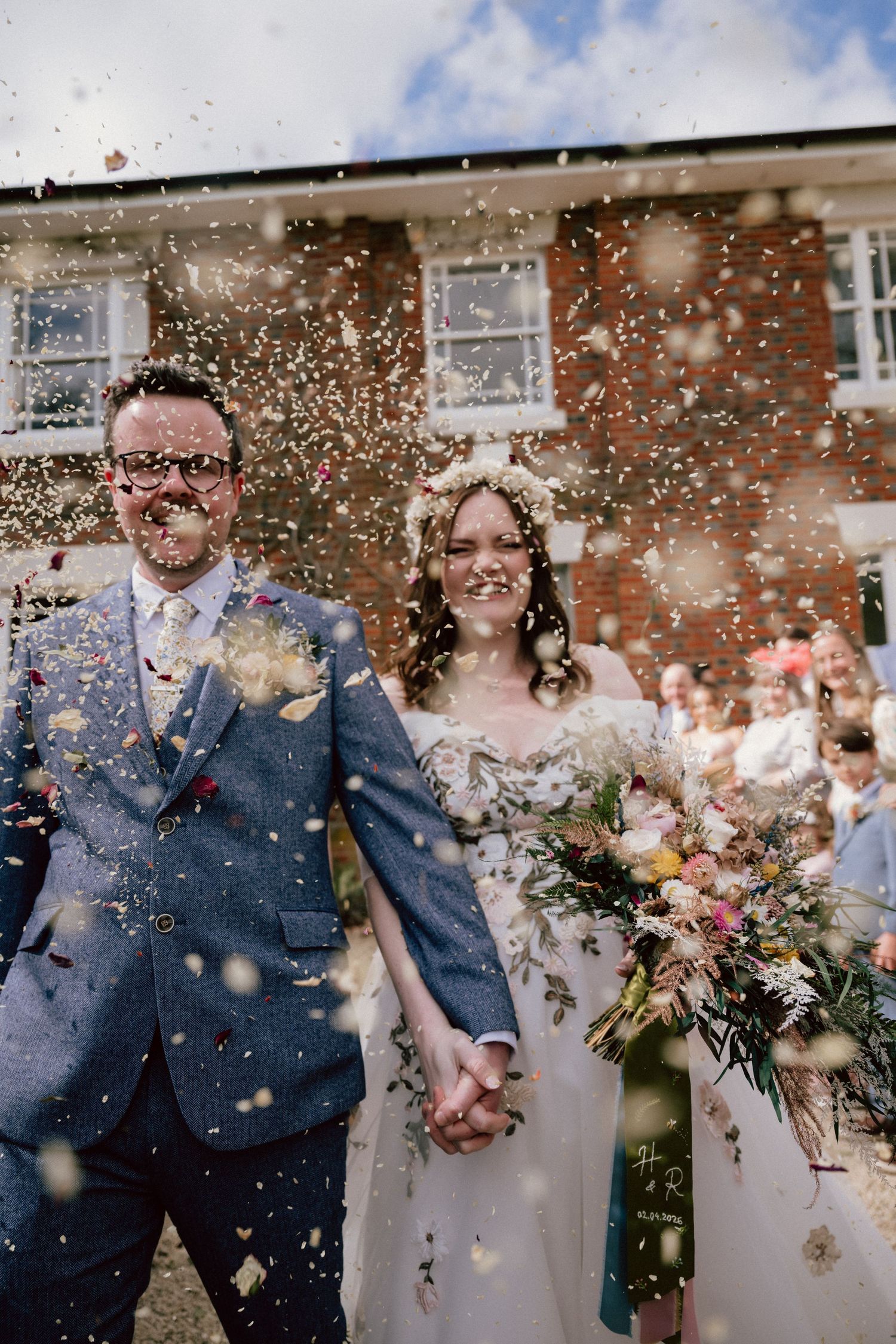 A bride and groom enjoy walking through confetti following their outdoor wedding ceremony at the ridgeway barns in wroughton, swindon
