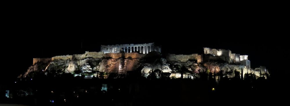 Night view of the illuminated Acropolis perched on hilltop in Athens.