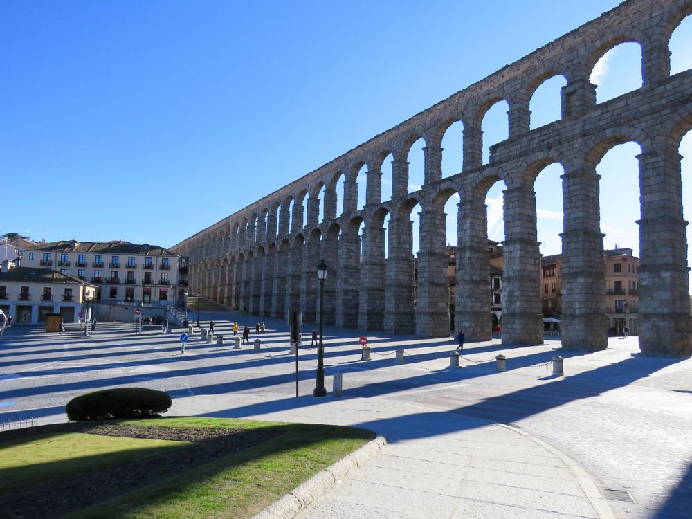 Ancient Roman aqueduct with multiple arches stretches across plaza in Segovia, Spain.