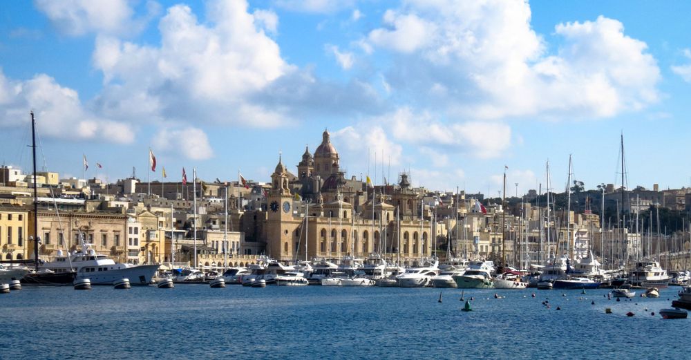 Panoramic view of Valletta harbor with historic architecture and moored boats.