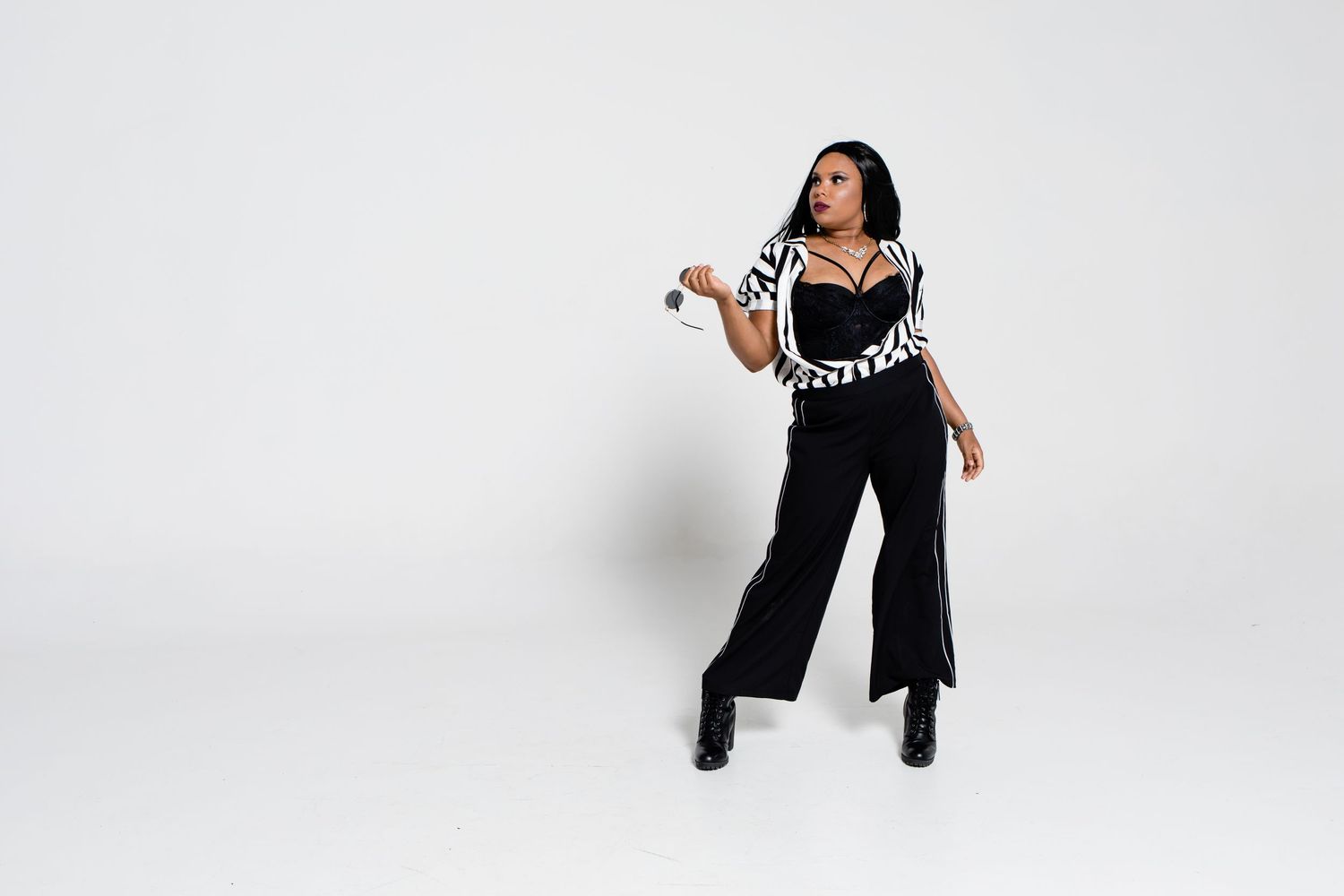A person wearing a black and white checkered top with black pants strikes a dynamic pose against a white background.