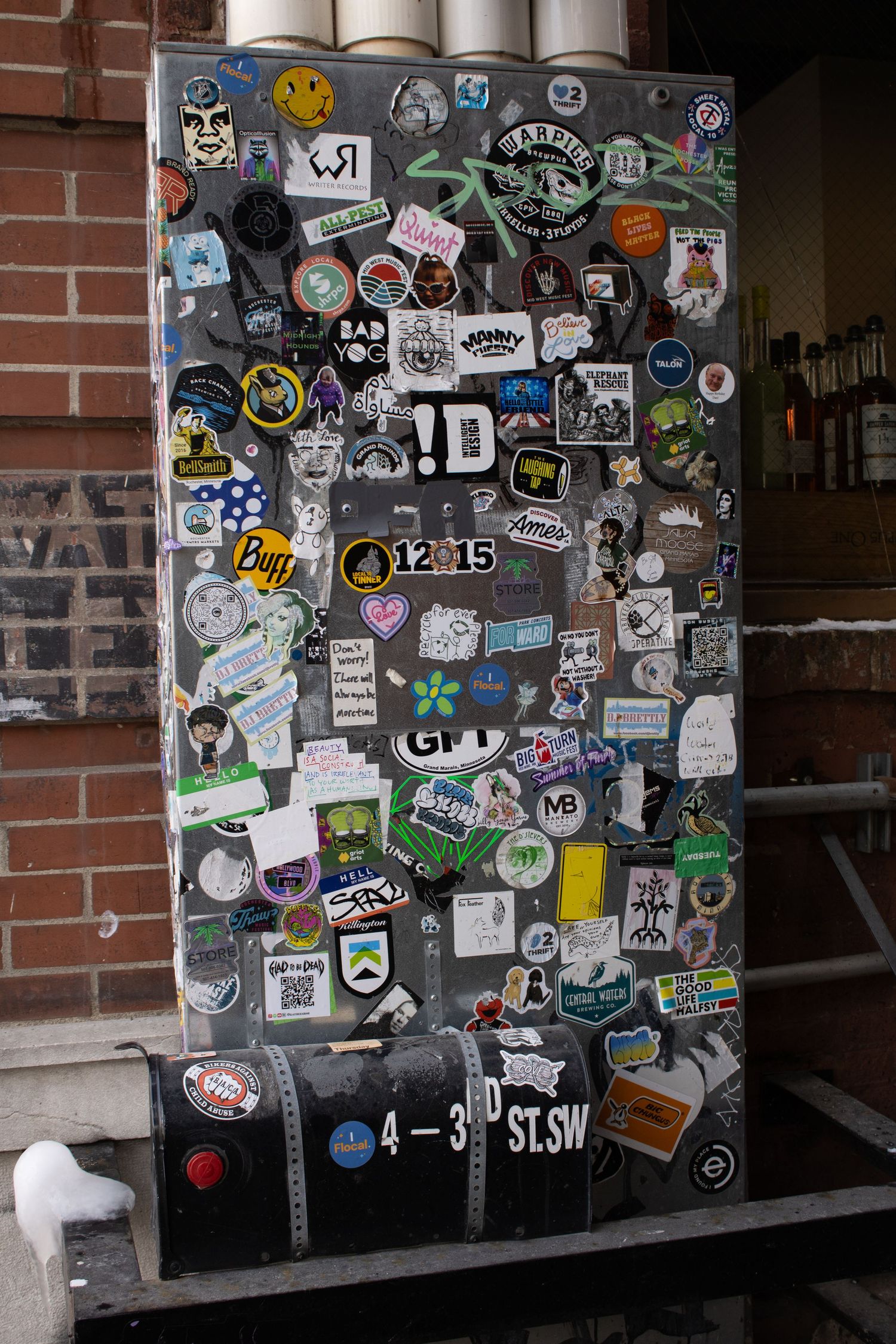 A door covered in various stickers, badges and street art creates an urban collage.