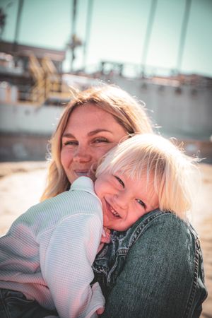 Mother and child sharing joyful moment at beach.