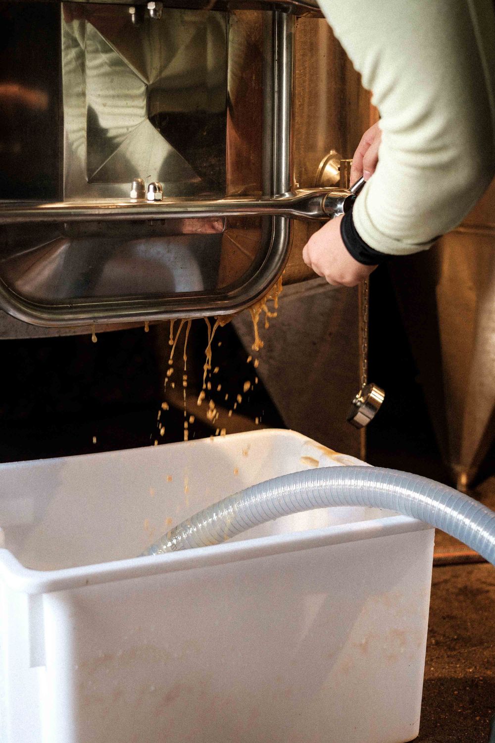 Wine being poured through processing equipment into white collection container.