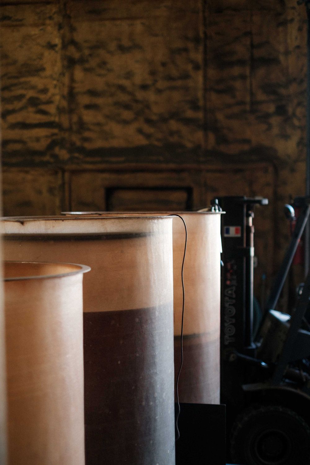 Large industrial storage drums lined up in a dimly lit warehouse.