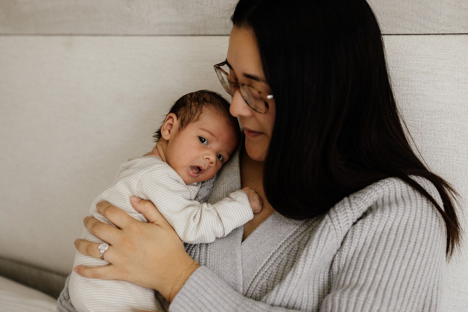 Mom snuggles newborn baby boy at in-home baby photoshoot in San Jose