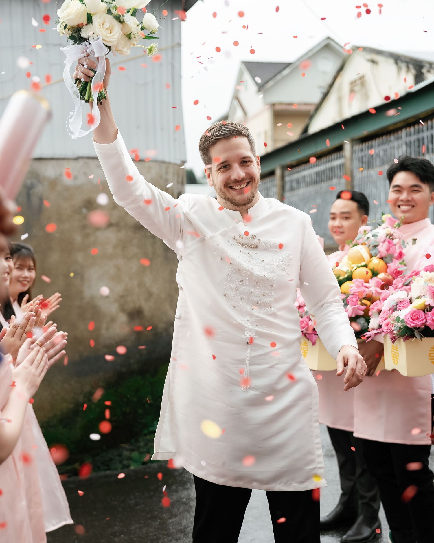 A wedding celebration with people throwing flower petals in the air as confetti while joyfully celebrating outside.