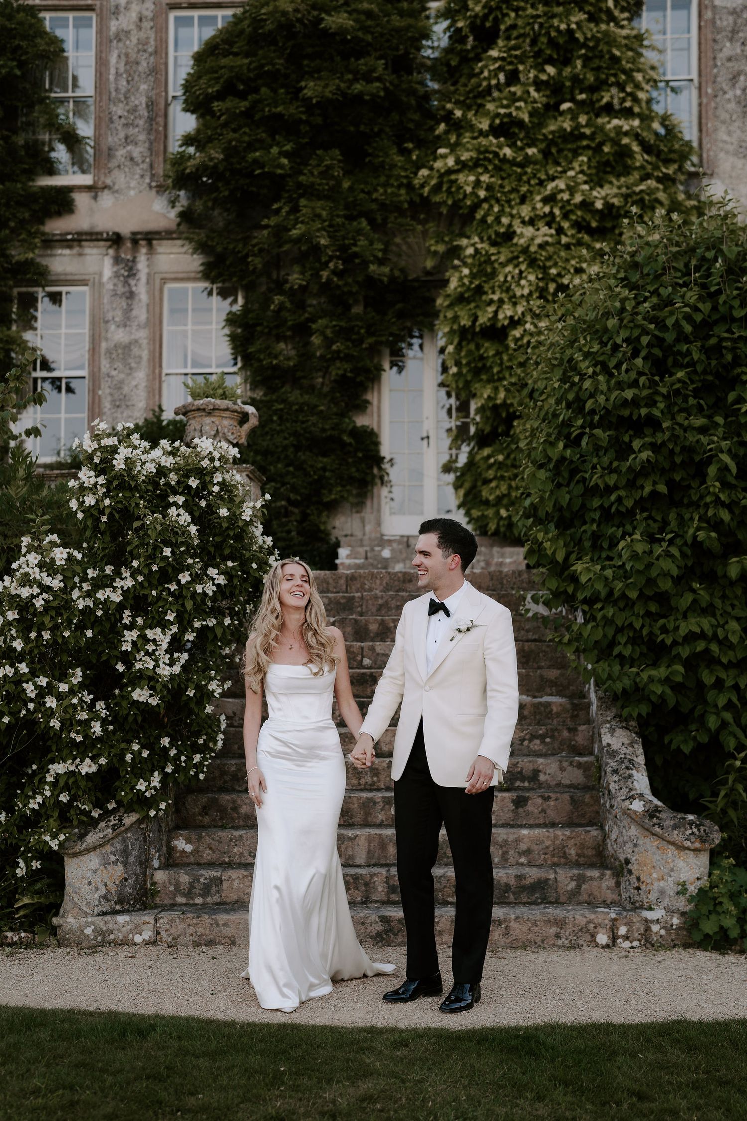 bride and groom on steps laughing with each other at hasmwell house wedding in bath