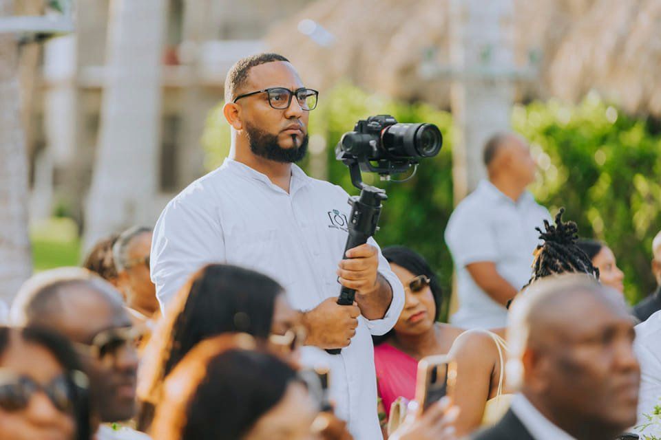 Videographer uses professional camera equipment to capture footage during an outdoor event.