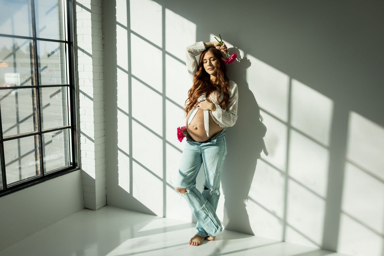Lifestyle maternity photography with expecting mother holding flowers in a casual outfit at a Calgary studio