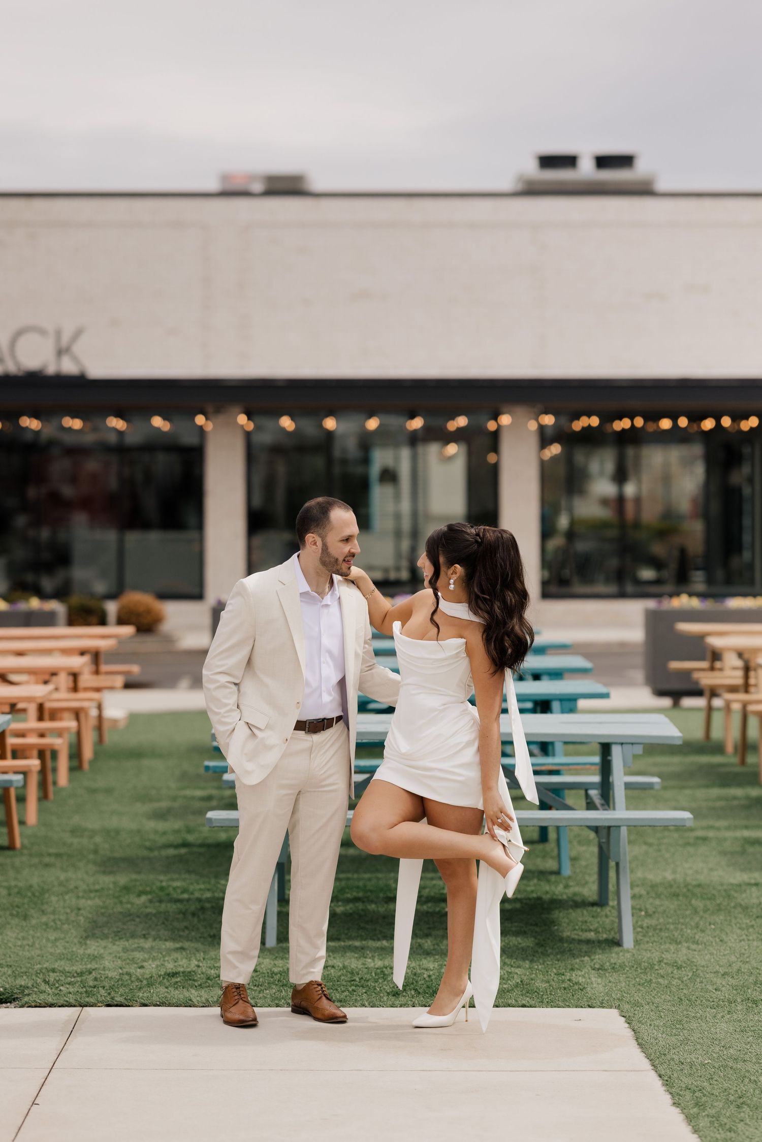 A romantic beach engagement photo of a couple in white clothing at sunset.