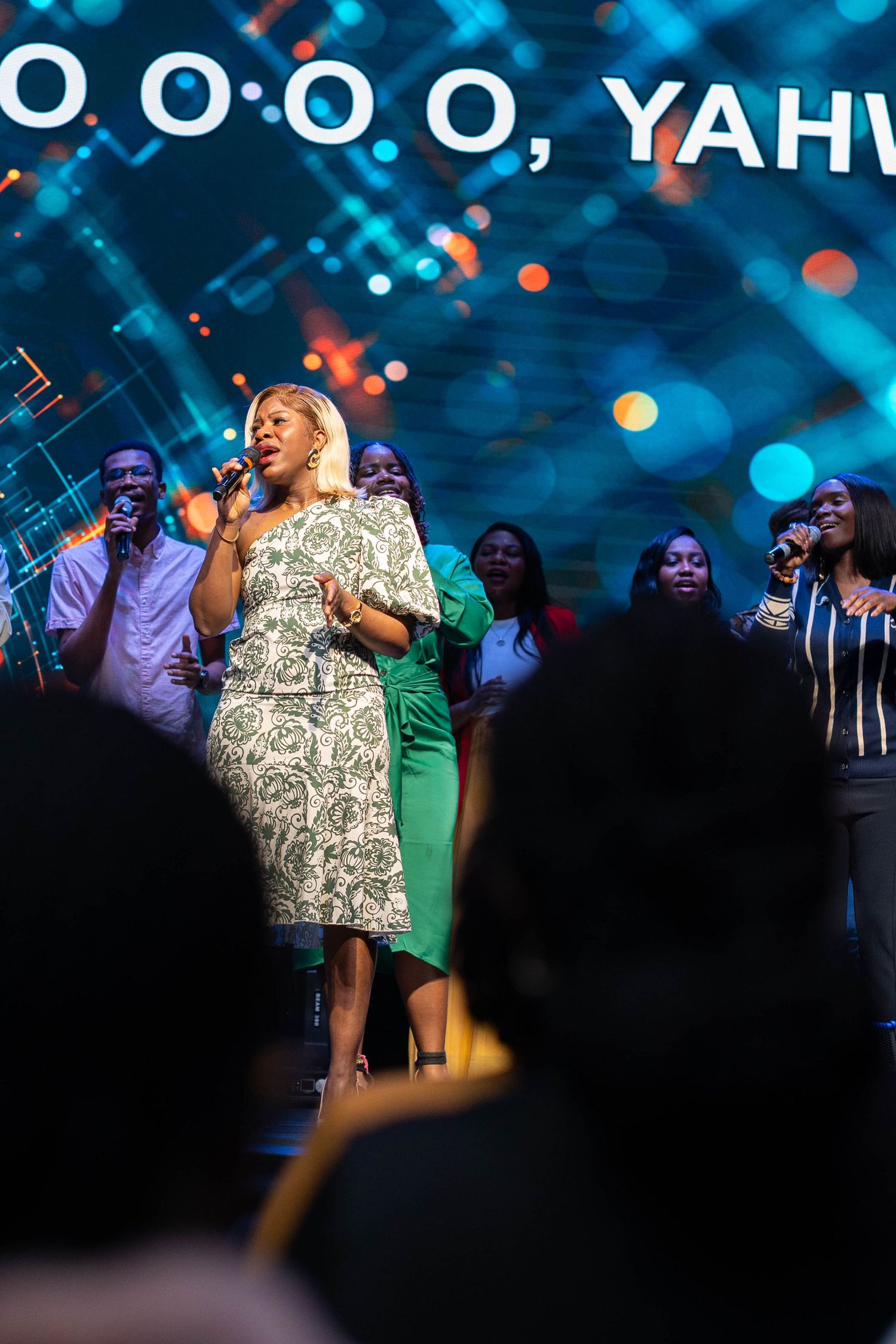 Performers singing on stage with a starry blue backdrop during a musical performance.
