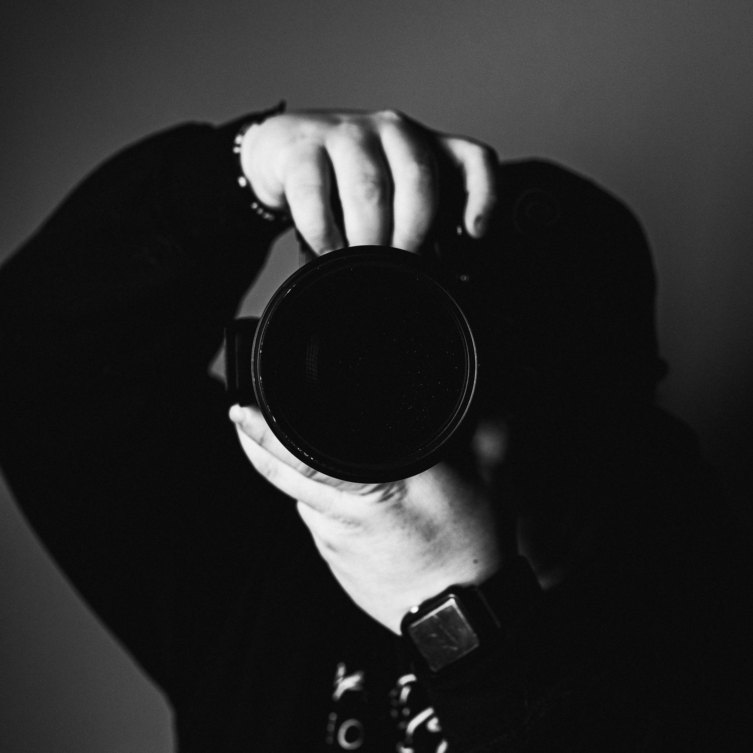 Closeup black and white self-portrait of owner Dakota DeGraw holding his Nikon camera