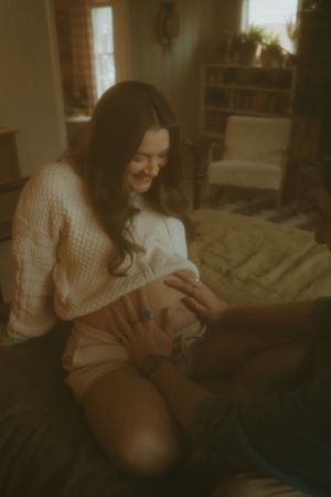Warm-toned intimate portrait showing joy and connection during a pregnancy moment.