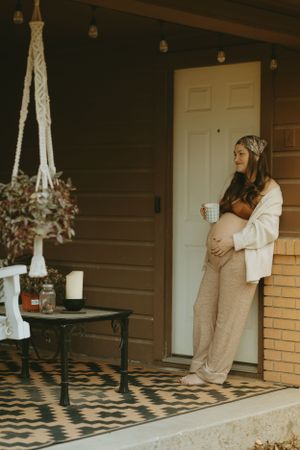 Maternity photoshoot on porch featuring bohemian decor and natural lighting.