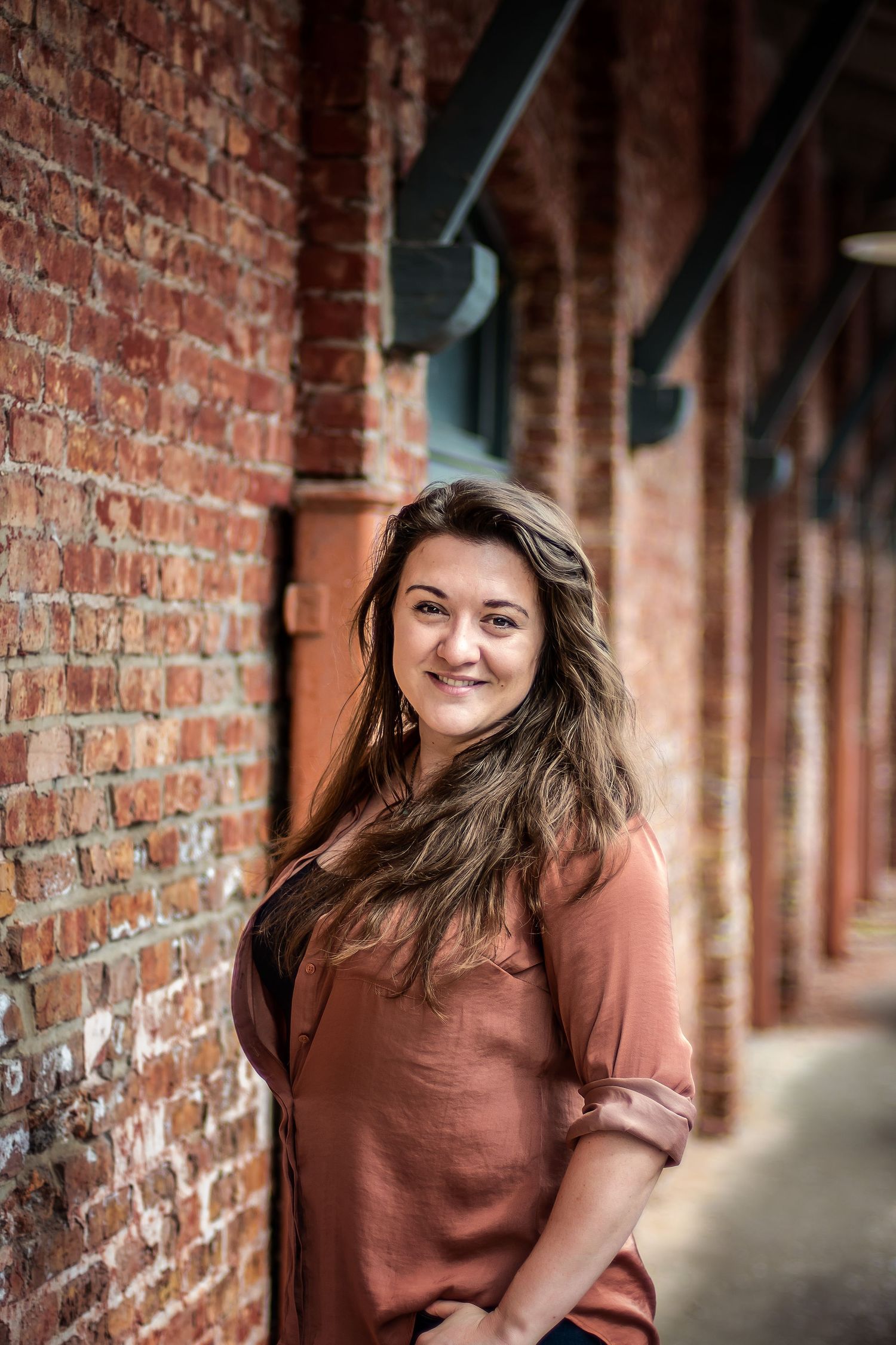 A rustic brick archway serves as backdrop for portraits against warm red walls.