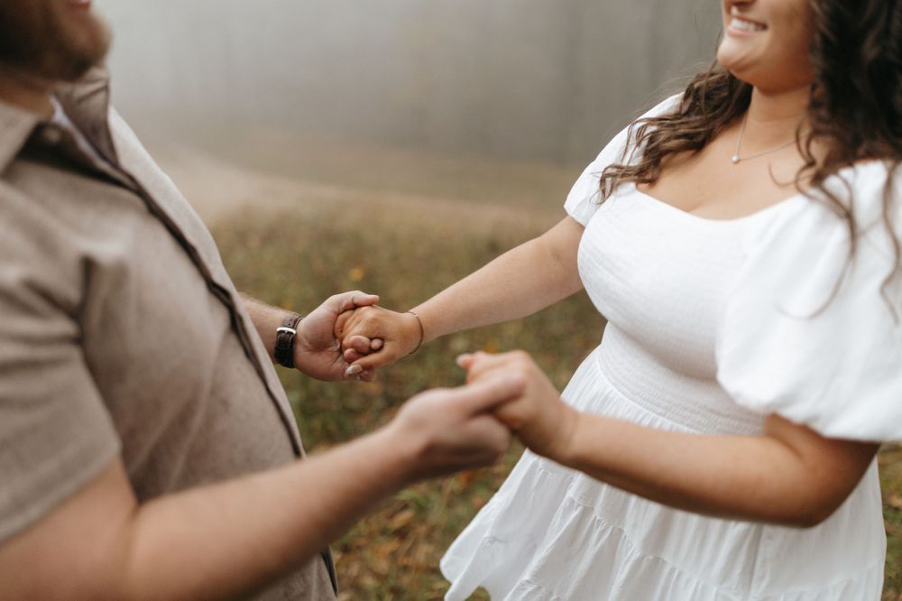 A couple holds hands in an intimate moment captured during their autumn photoshoot.