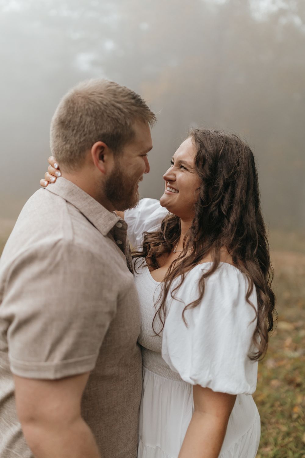A close-up shot of a couple sharing an intimate embrace in a misty forest setting.