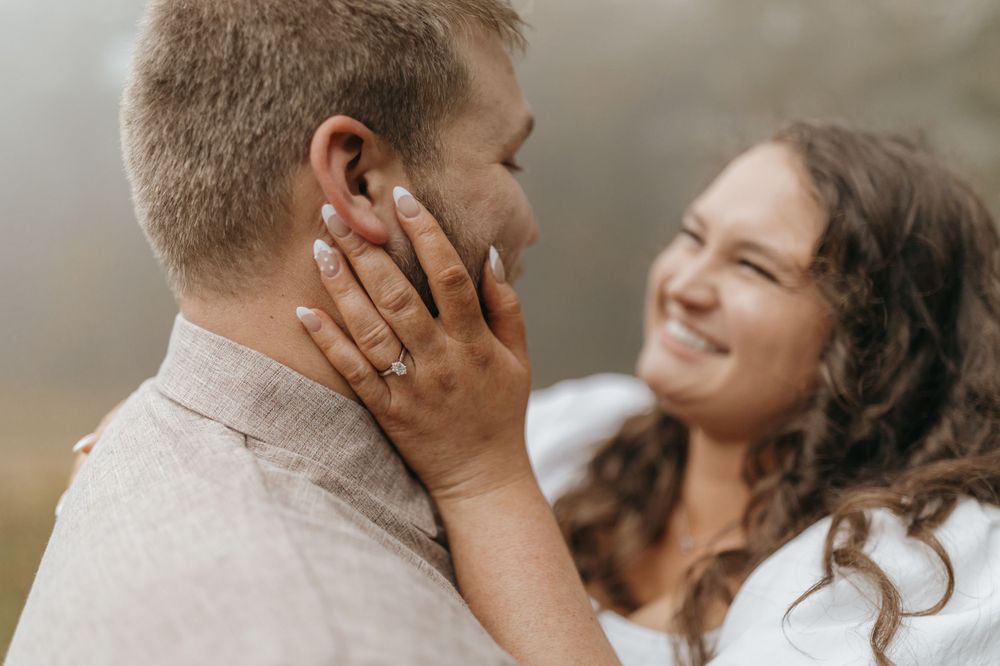 An intimate engagement photo showing hands caressing faces while sharing a loving gaze.