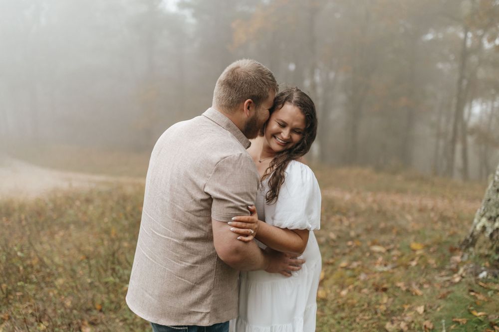 A couple sharing an intimate embrace on a misty autumn morning in nature.