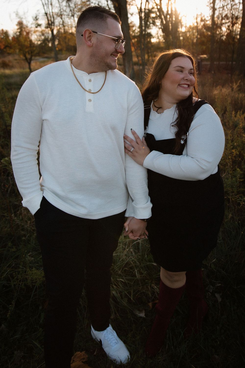 Couple enjoying sunset together in matching outfits against natural autumn backdrop.