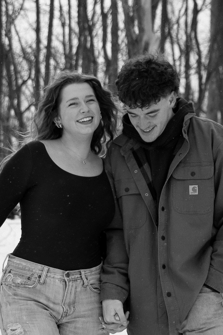 Couple laughing together during winter photoshoot in black and white.