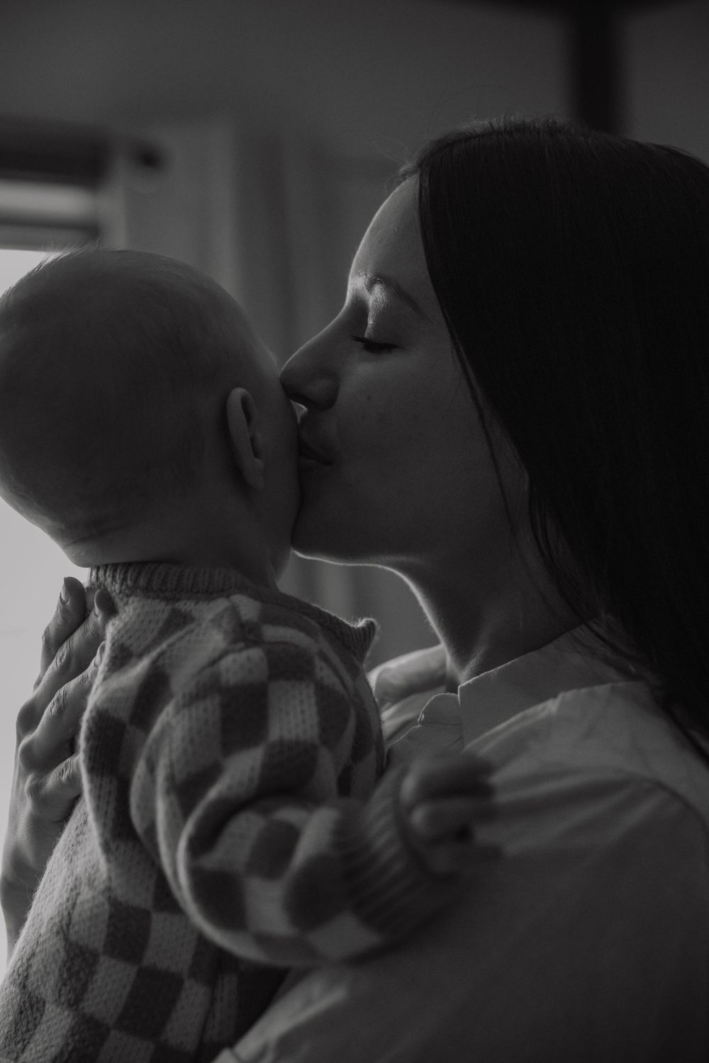A tender moment captured in black and white as a mother gives her baby a loving kiss.
