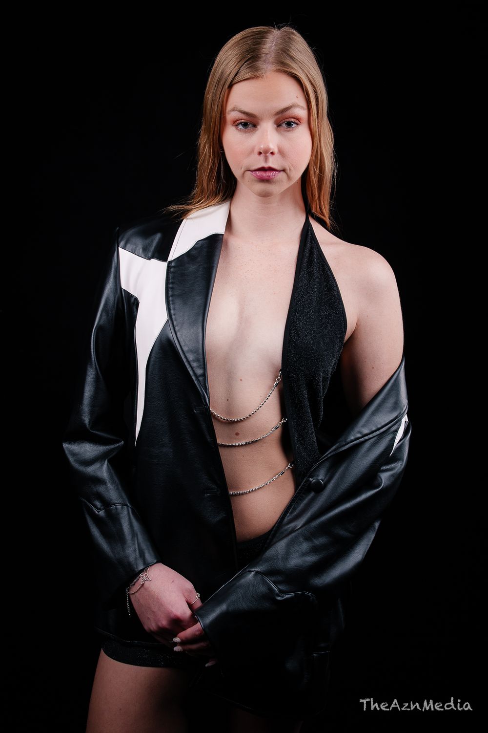 Studio fashion portrait featuring black leather jacket and chain detail styling.