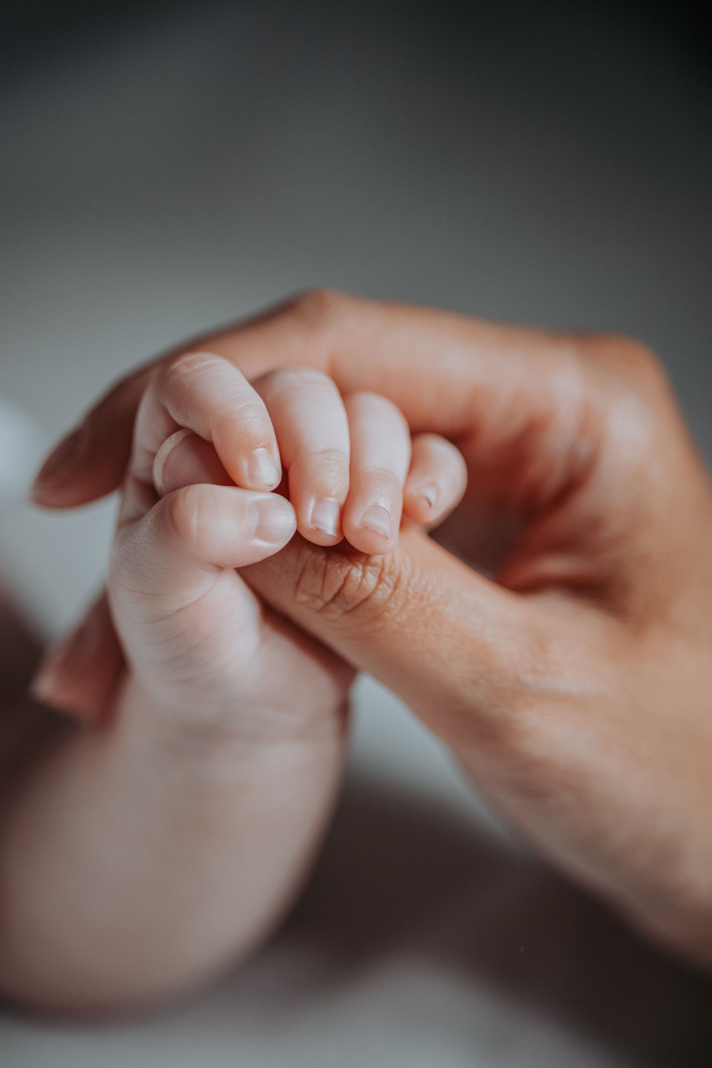 A tiny baby hand gently grasping an adult finger in a tender moment of connection.