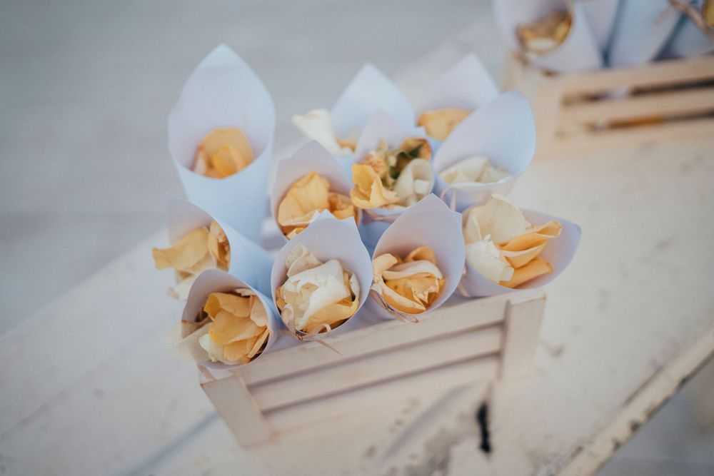 Small food cones filled with bite-sized appetizers arranged in a rustic wooden crate at a catered event.