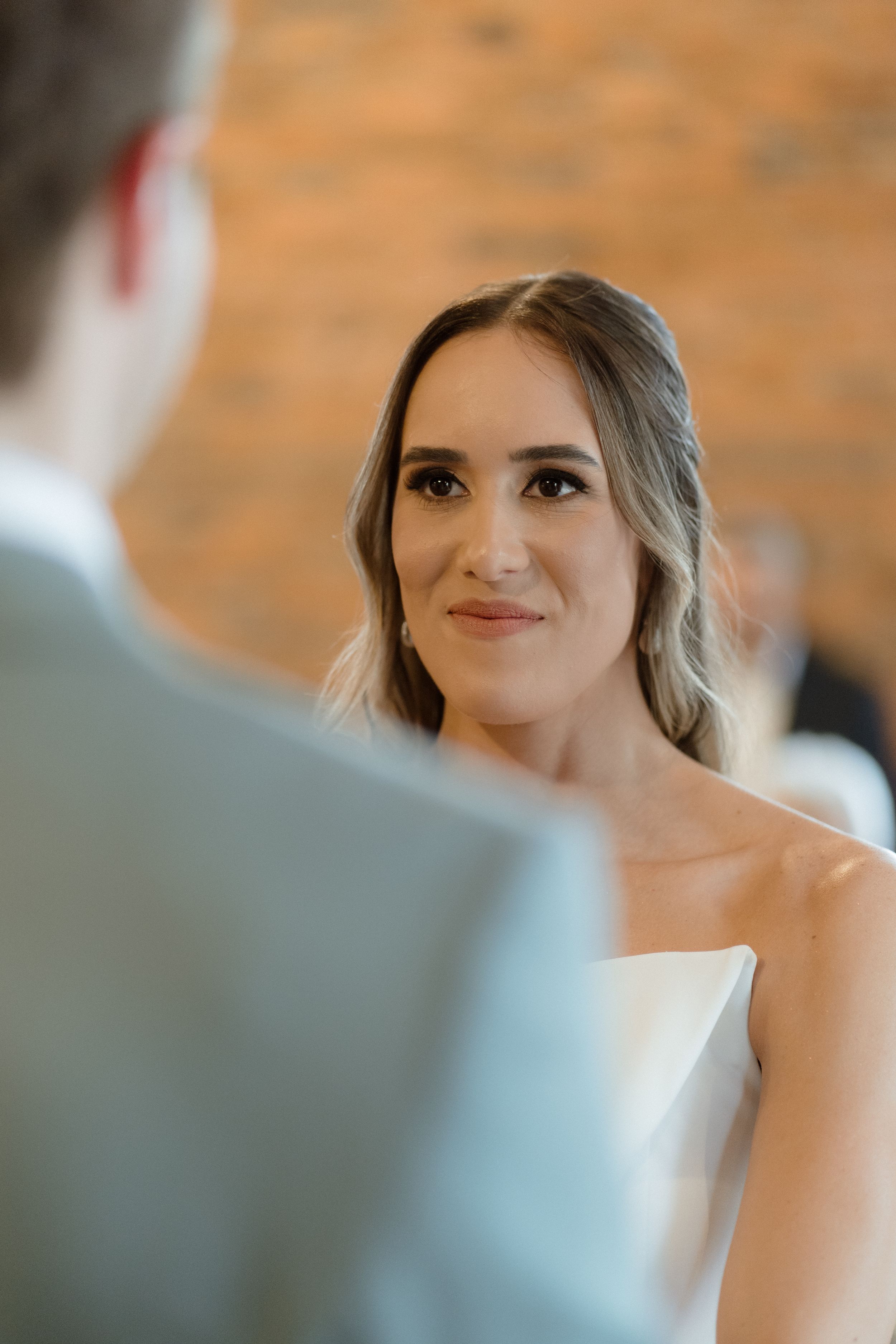 Intimate moment during wedding ceremony with brick wall backdrop.
