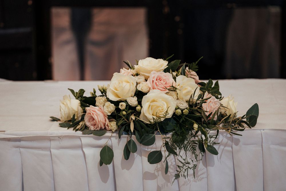 An elegant floral centerpiece with white and pink roses arranged on a table with white linen.