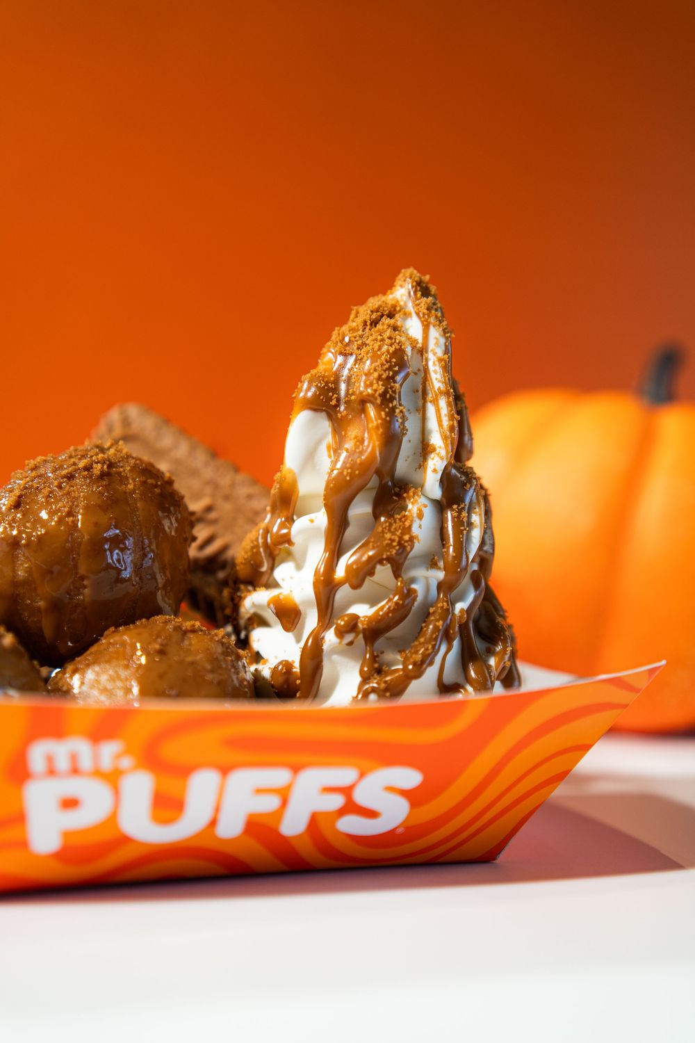 Chocolate-covered marshmallow candy pieces arranged in a row on an orange background, showing gooey texture and melted layers.