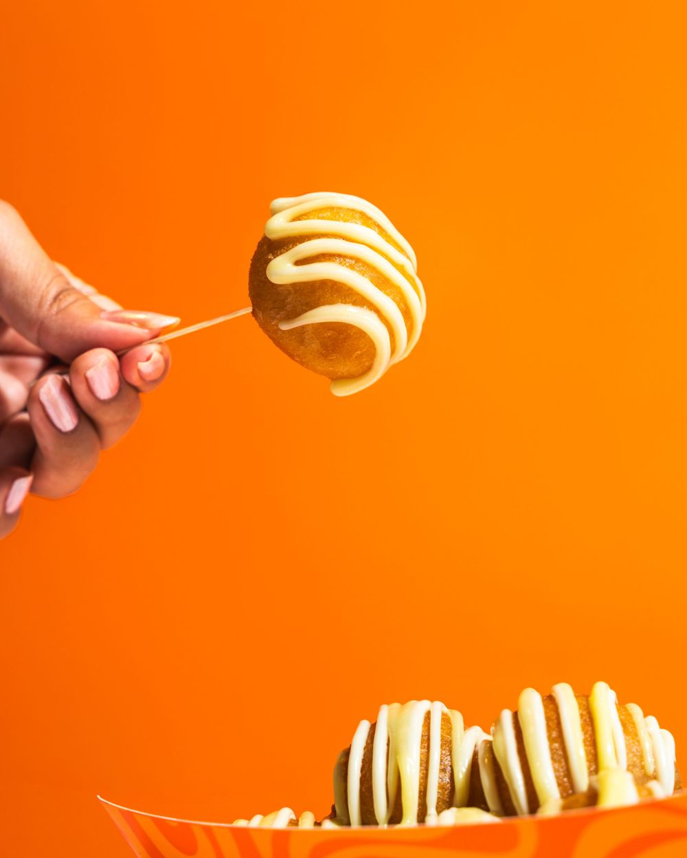 A series of chocolate-dipped strawberry candies arranged in a row against a bright orange background.