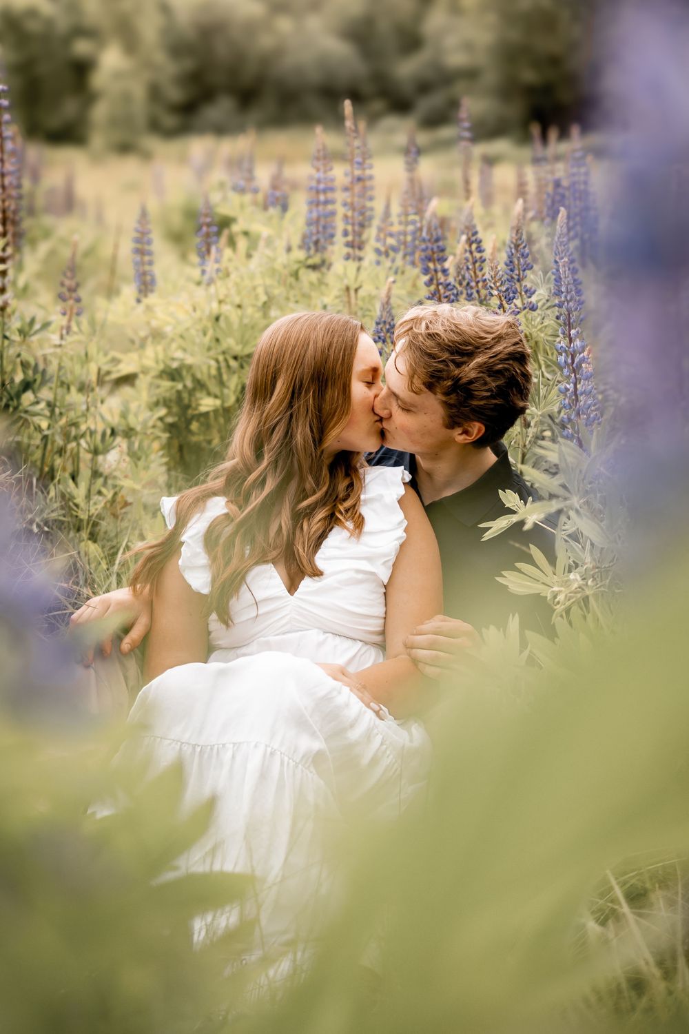 A romantic moment between two people surrounded by blooming purple lupine flowers.