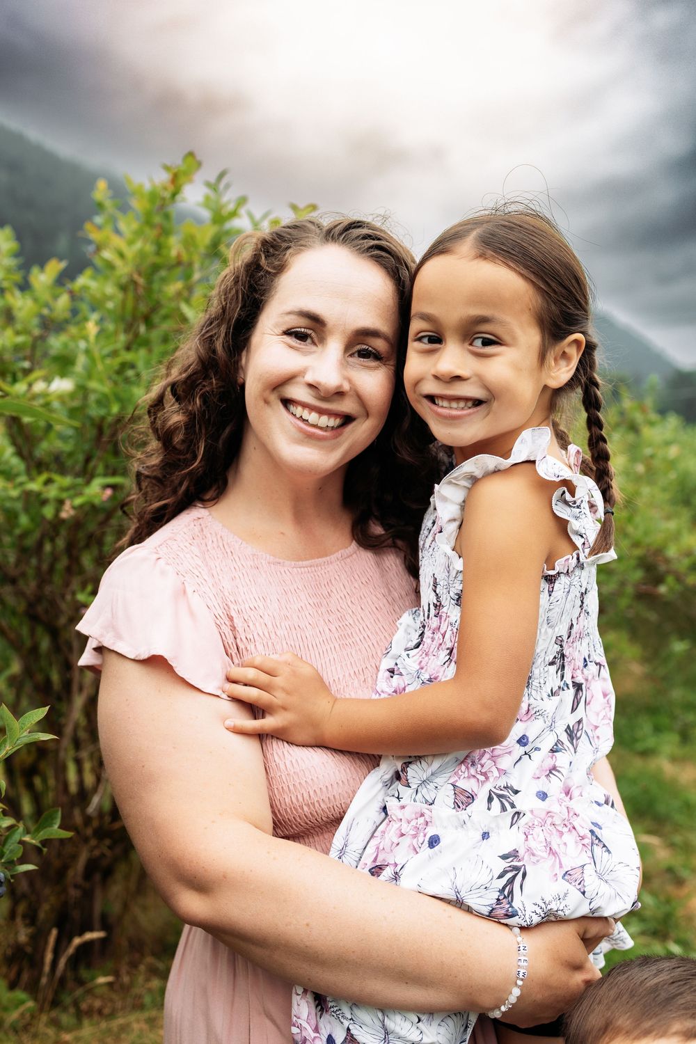 Two people share joyful embraces and laughter while posing in an outdoor nature setting.