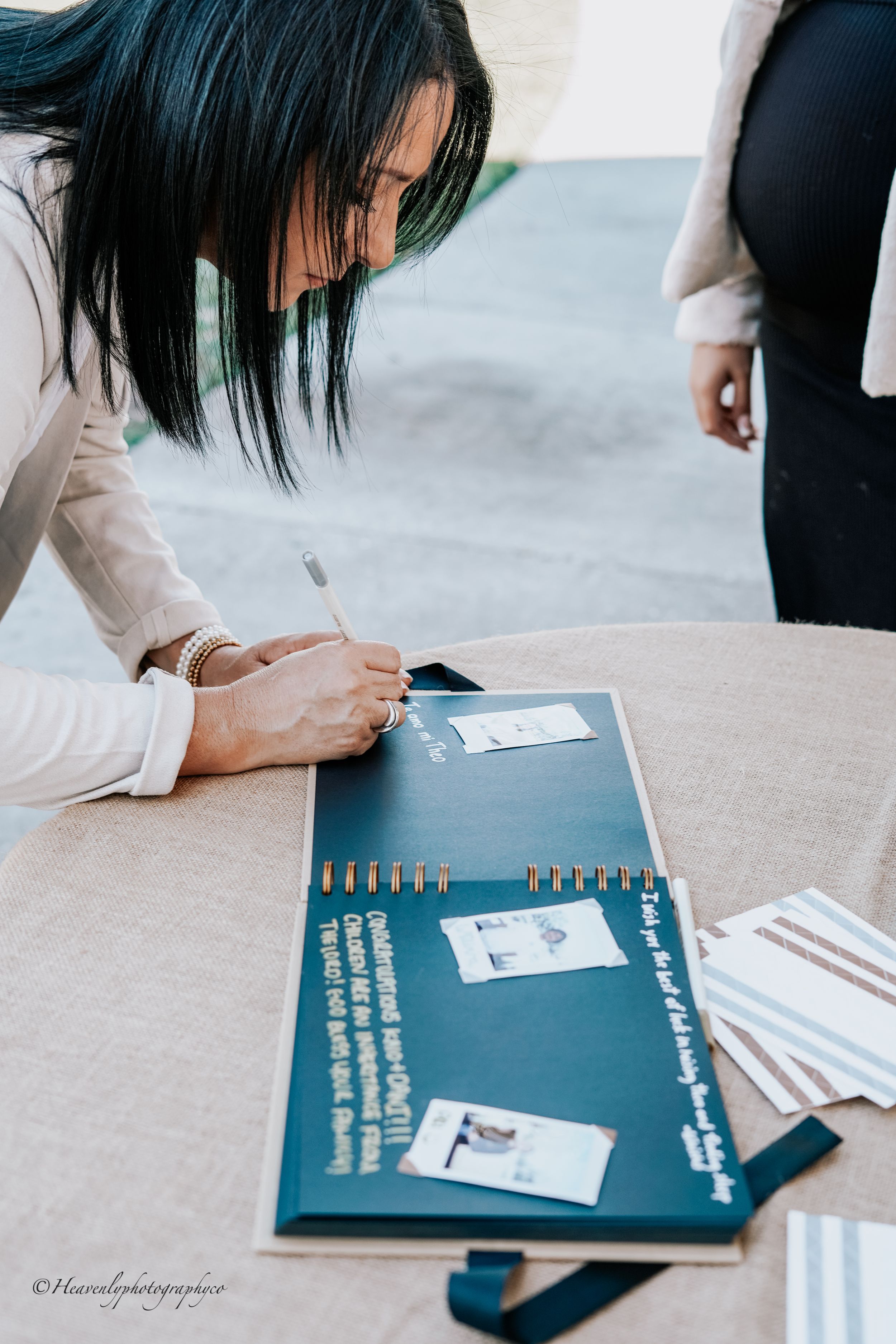 Person signing a dark blue guestbook or album at a special event.