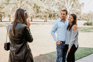 Photographer capturing a couple during an outdoor photoshoot in a park setting.
