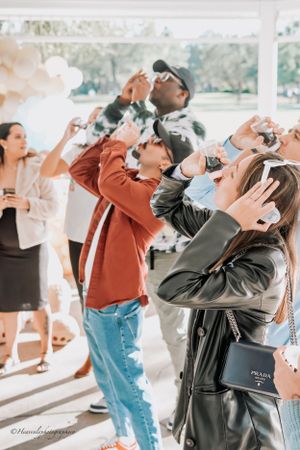 Group of guests participating in a baby shower game with bottles.