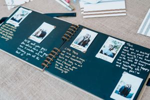 Open photo album with handwritten notes and polaroid pictures on dark blue pages.