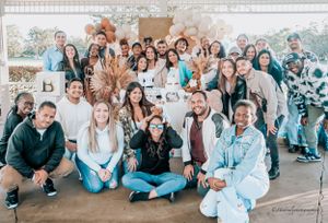 Large group photo of baby shower attendees gathered on an outdoor patio.