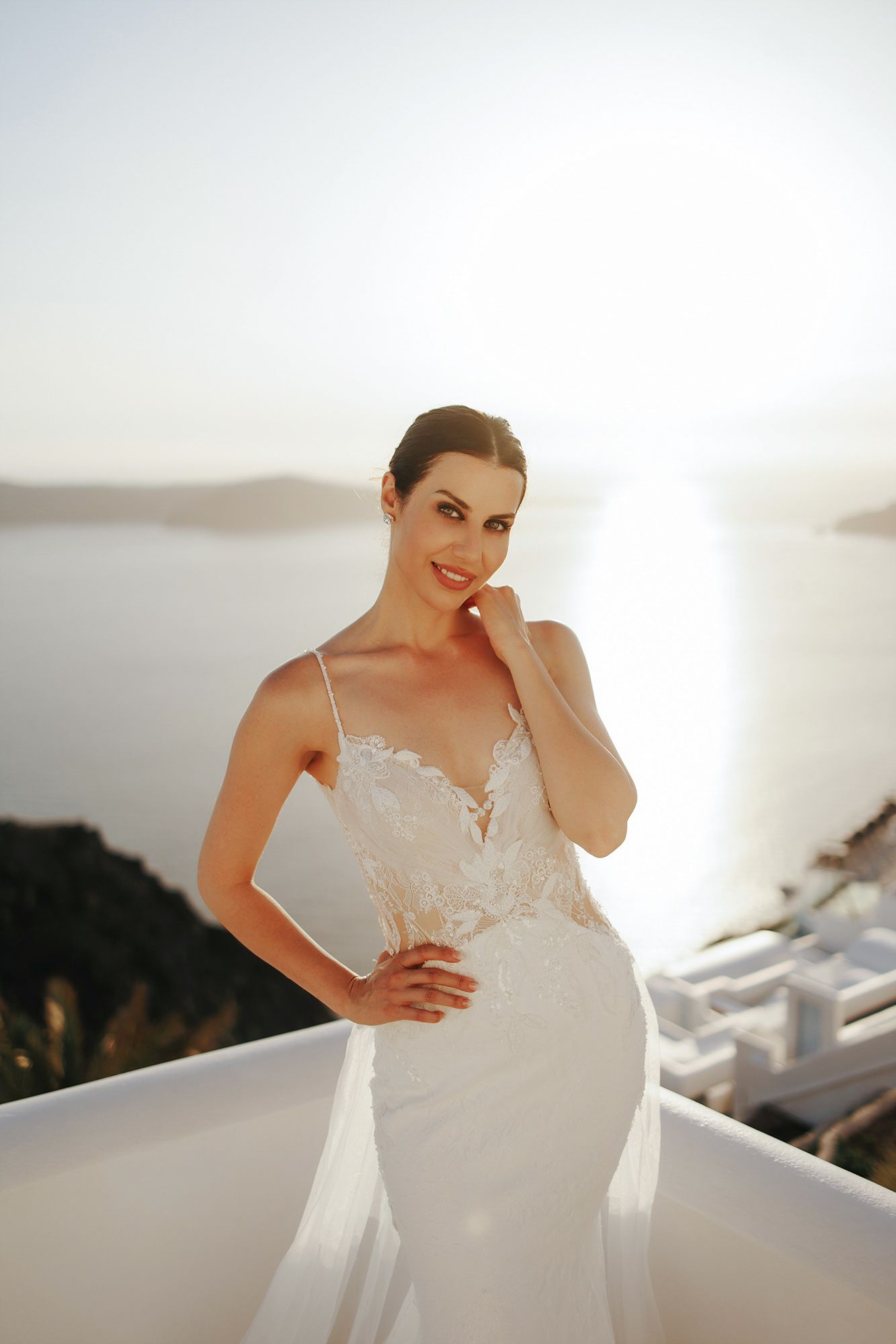 Beautiful wedding dress with delicate lace details and fitted silhouette photographed at sunset in Santorini, Greece.