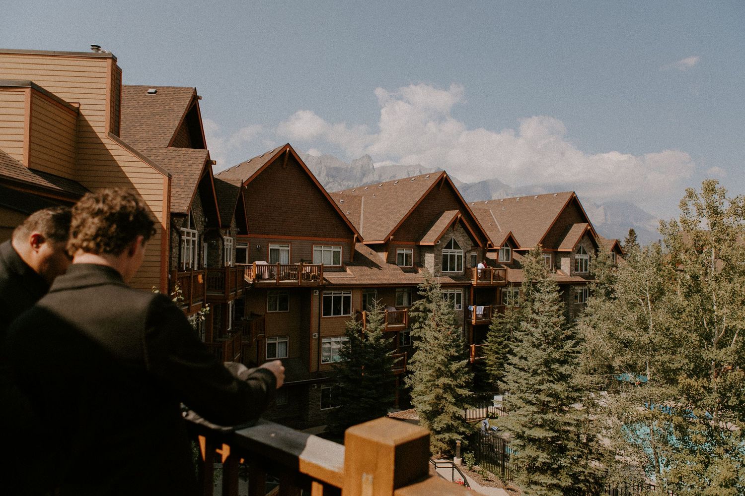 Mountain resort lodge buildings with wooden architecture nestled among evergreen trees on a sunny day.