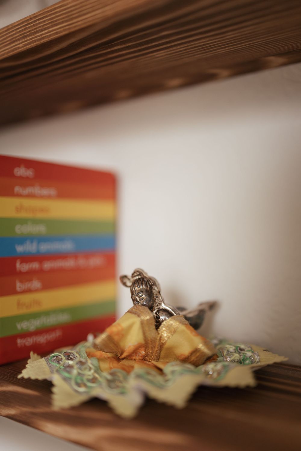 Close-up of a colorful rainbow book spine and small decorative figure on a wooden shelf.