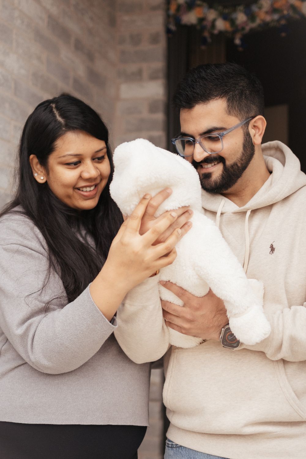 A couple shares a joyful moment together while holding a white plush toy or stuffed animal.