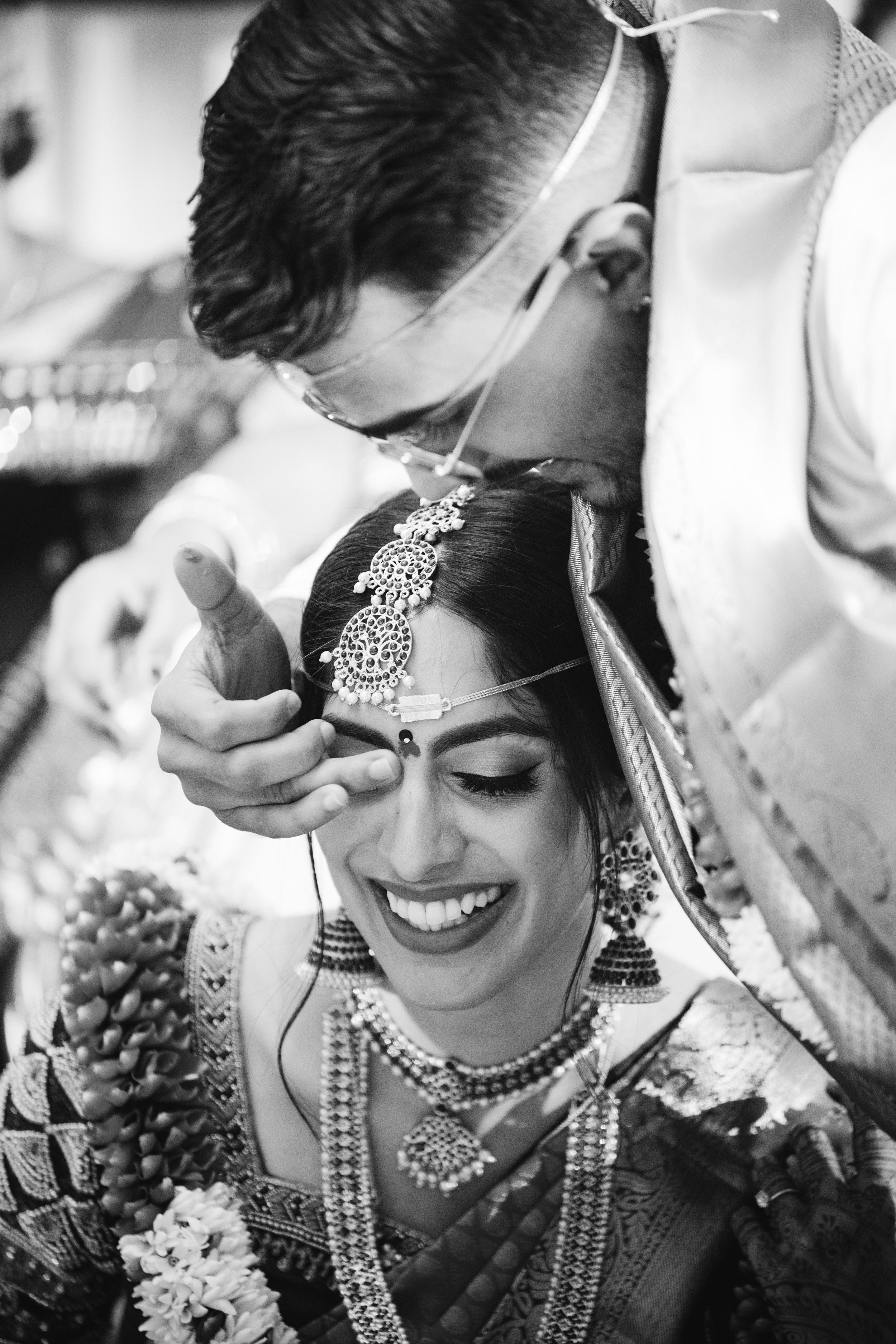 Emotional South Asian wedding moment at The Imperia in Franklin, NJ — groom ties the mangalsutra as bride smiles in joy.