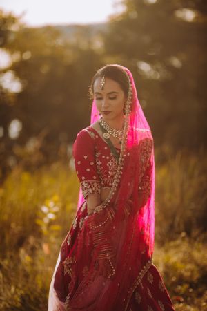 Sunlit bridal portrait in red lehenga at Hyatt Regency Chesapeake Bay Golf Resort, Spa and Marina—South Asian wedding elegance.